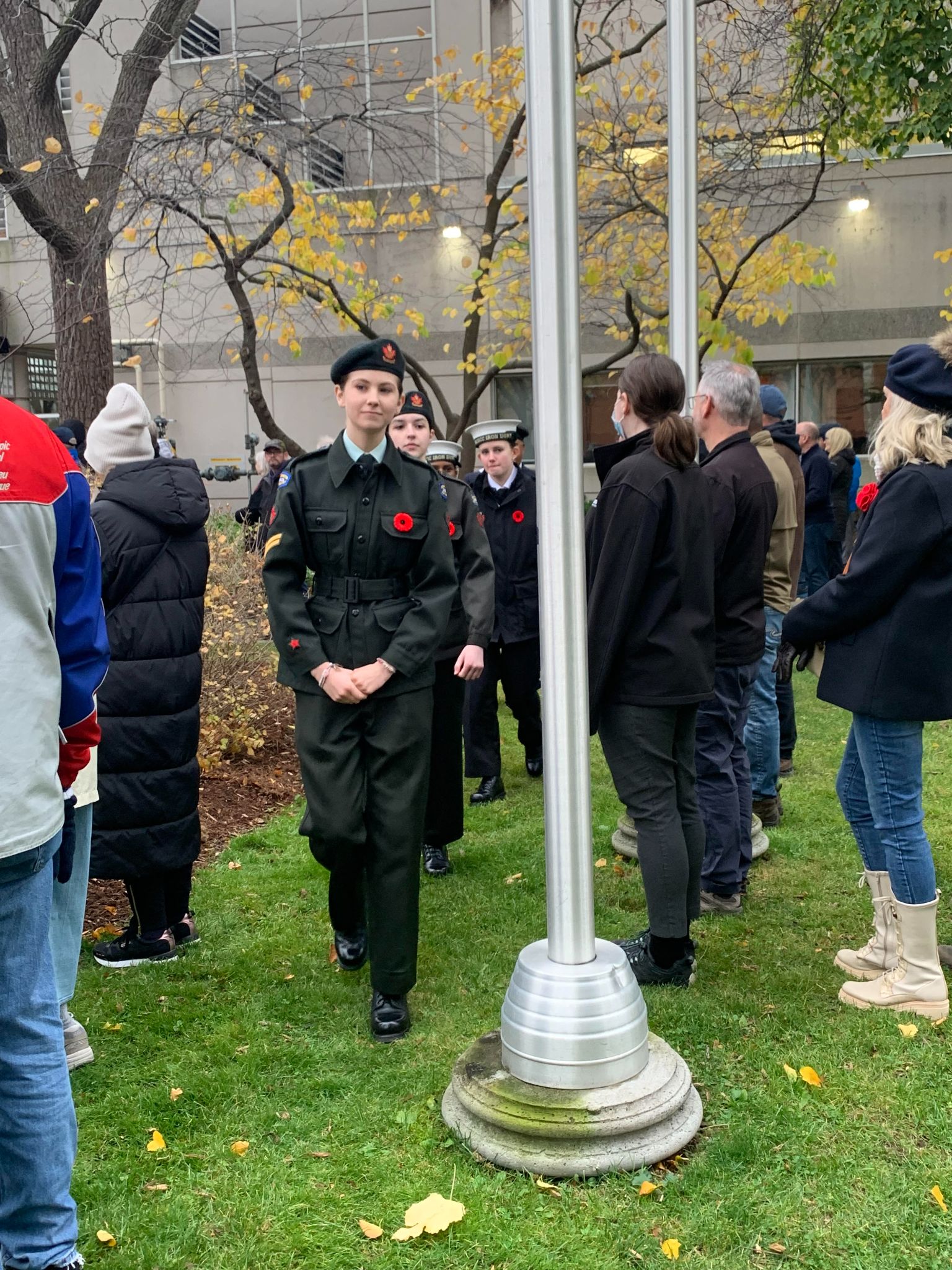 Cadets posted at the memorial with attendees in the background