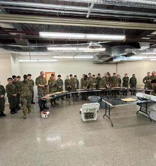 Wide indoor training overview with cadets and instructors gathered for activity instruction