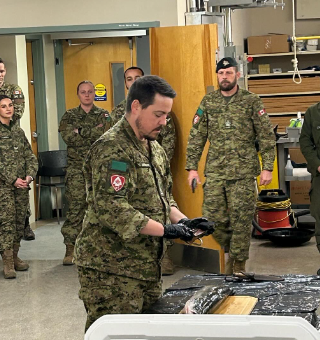 Cadets and instructors gathered around a table during a practical demonstration