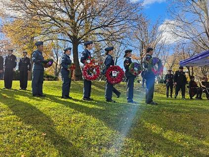Army, sea, and air cadets lined up at attention beside memorial headstones